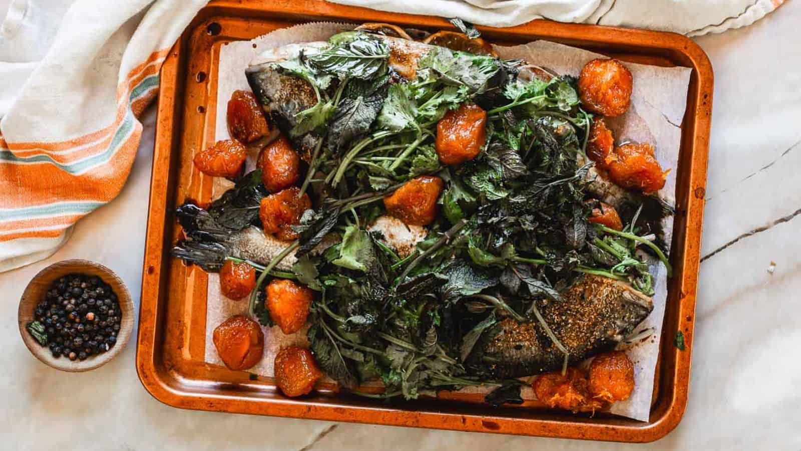 A baking sheet with fish and greens on it.