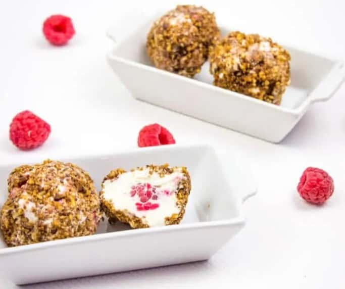 Raspberry cheesecake bites on a white plate.