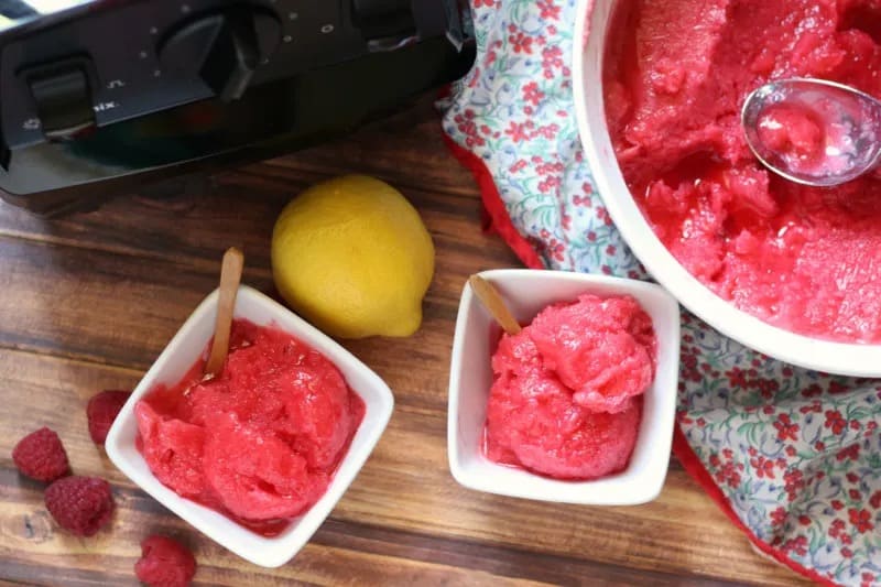 Two bowls of raspberry lemonade sorbet and a blender.