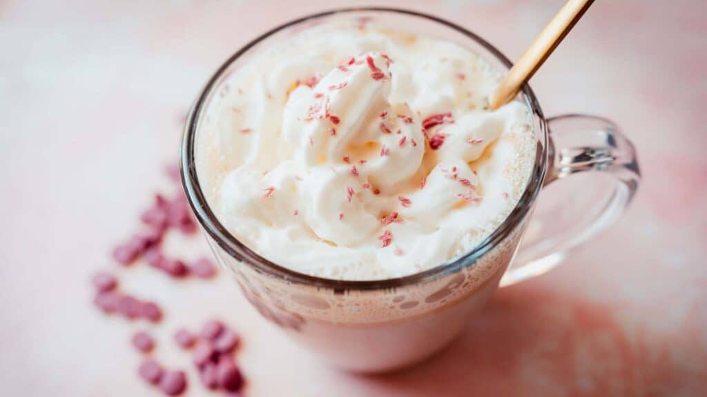 A cup of hot cocoa with whipped cream and sprinkles.