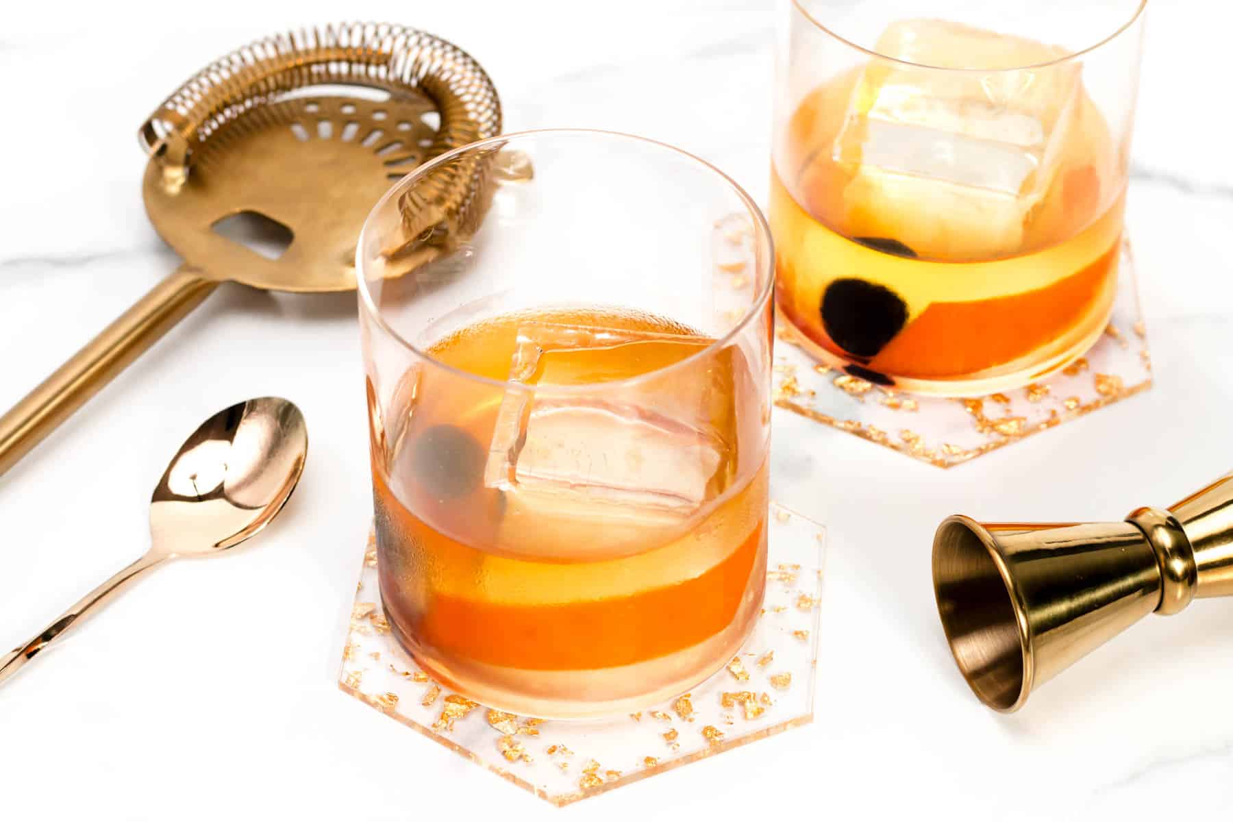 Two glasses with ice and a spoon next to them, perfect for serving a refreshing Scotch Old-Fashioned cocktail.
