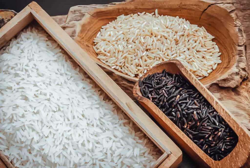 Black and white rice in wooden boxes on a wooden table.