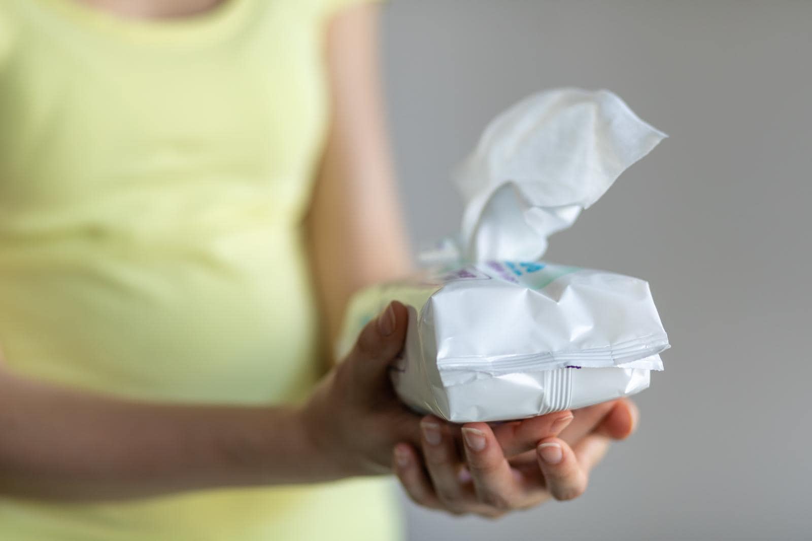 A woman is holding water baby wipes in her hands.