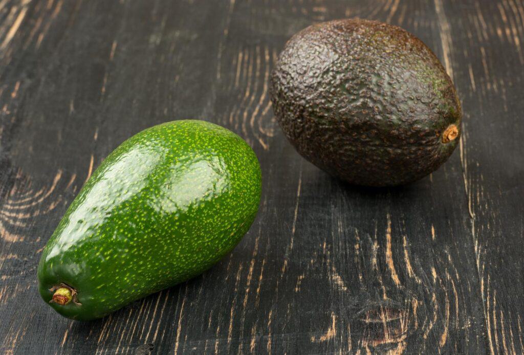 A guide on how to buy two fresh avocados from a wooden table.
