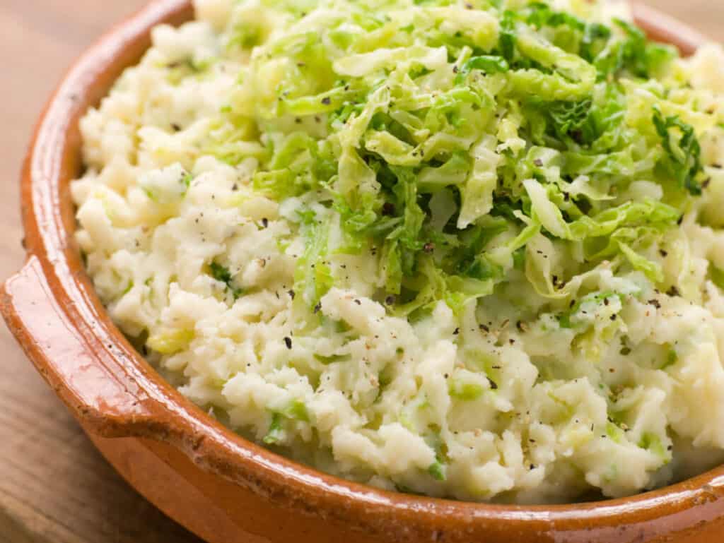 A bowl of mashed potatoes with cabbage.