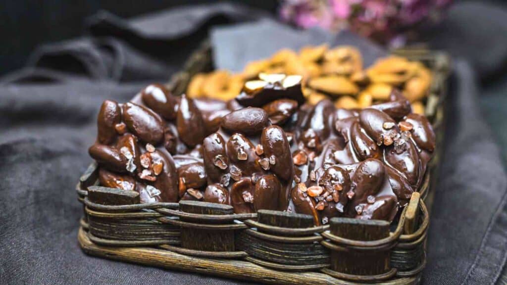 A wicker basket filled with chocolate covered nuts.