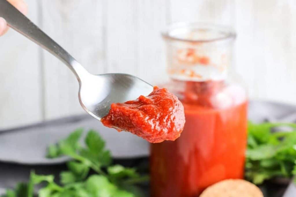 A spoonful of tomato sauce in a jar.