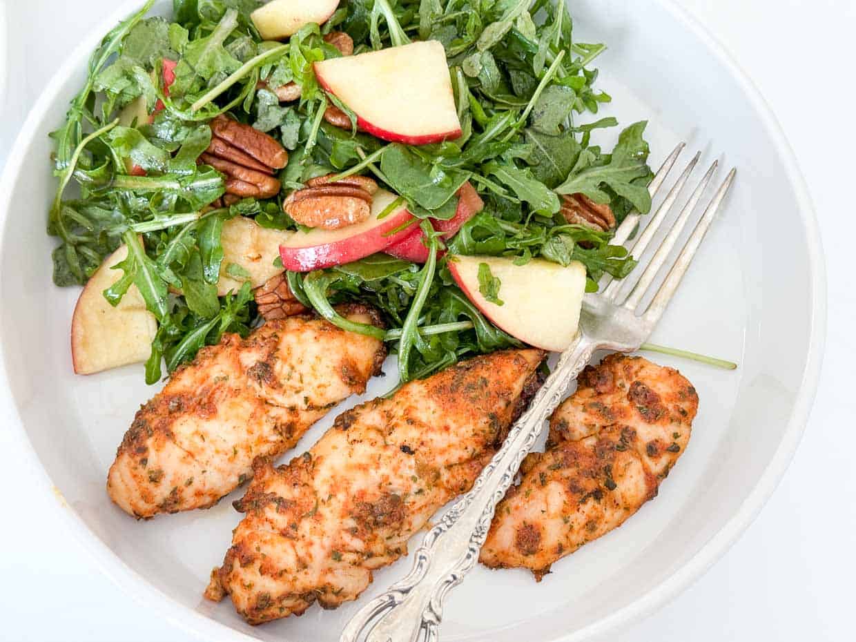 Ranch baked chicken next to a rocket salad.