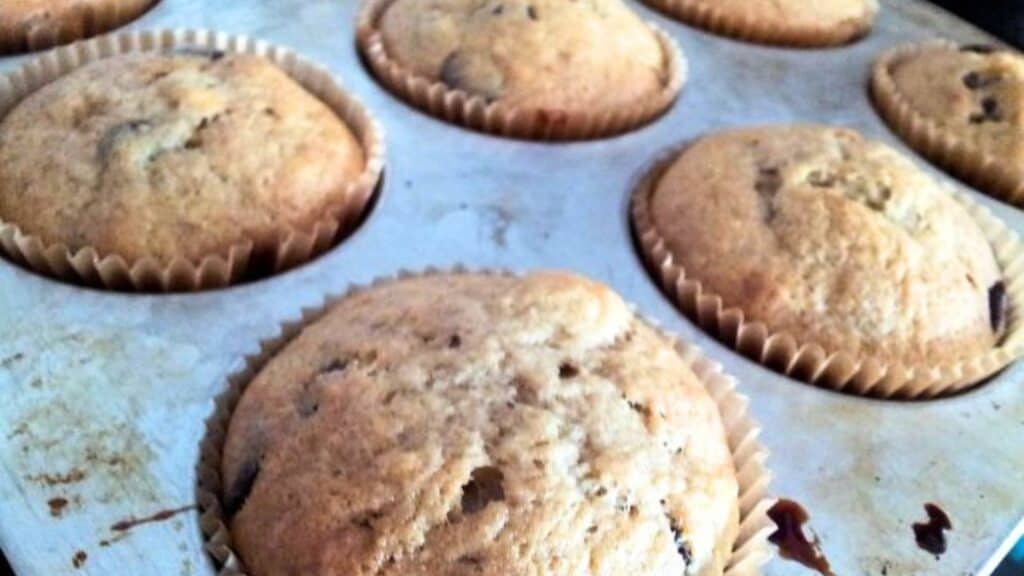 Image shows banana Chocolate chip muffins in a muffin tin.