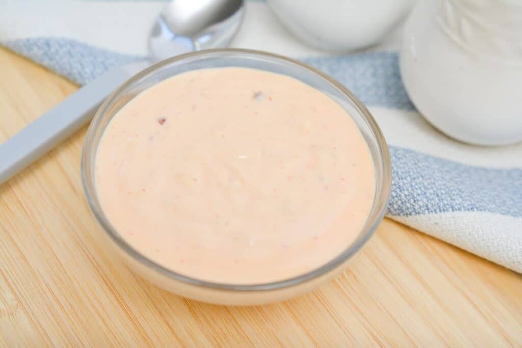 A bowl of orange sauce on a wooden table.