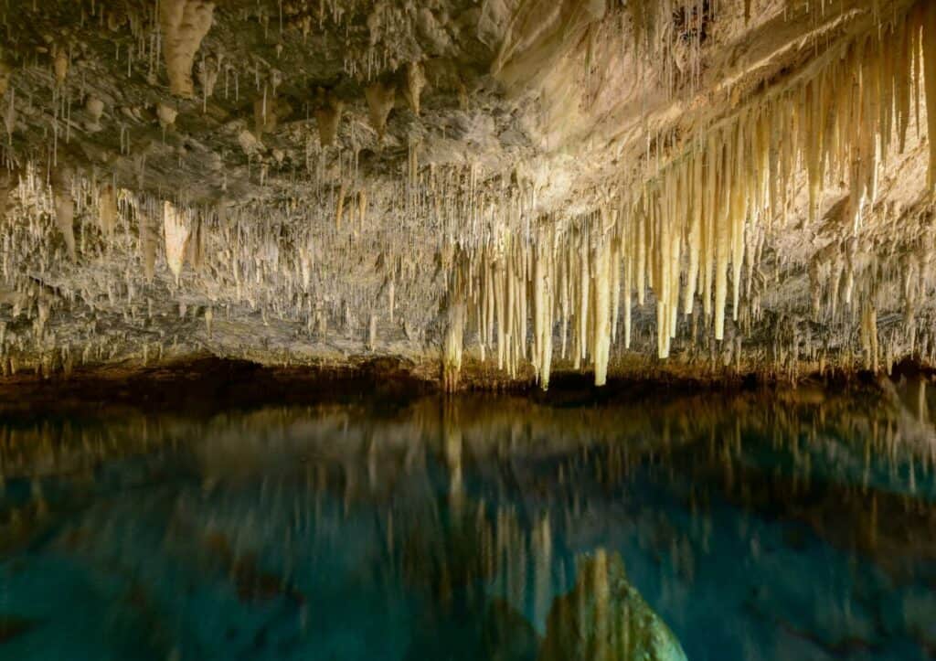 A cave with stalactites and stalagmites hanging from the ceiling.