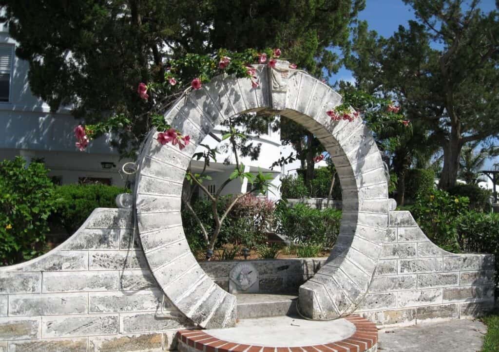 A stone archway with flowers in front of it.