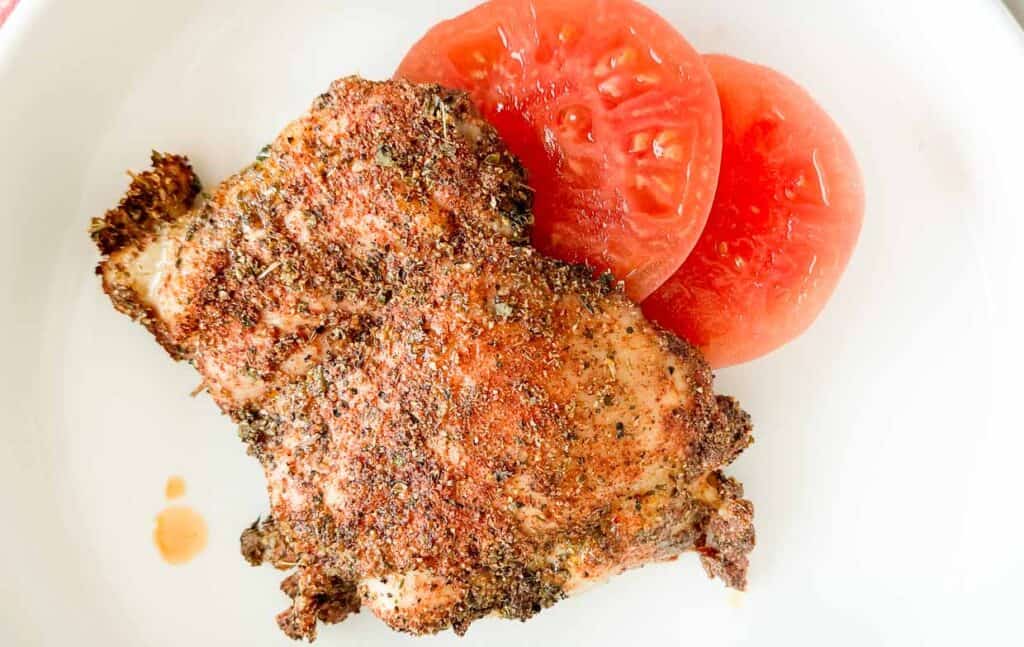 A deli plate with chicken and tomato.