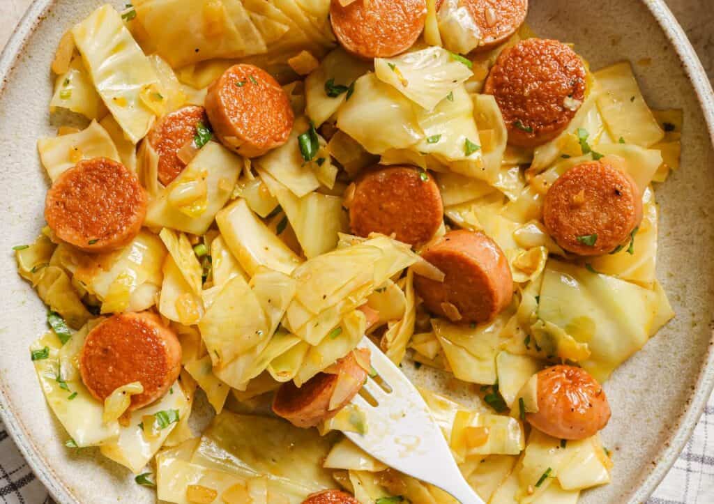 Cabbage and sausage on a plate with a fork.