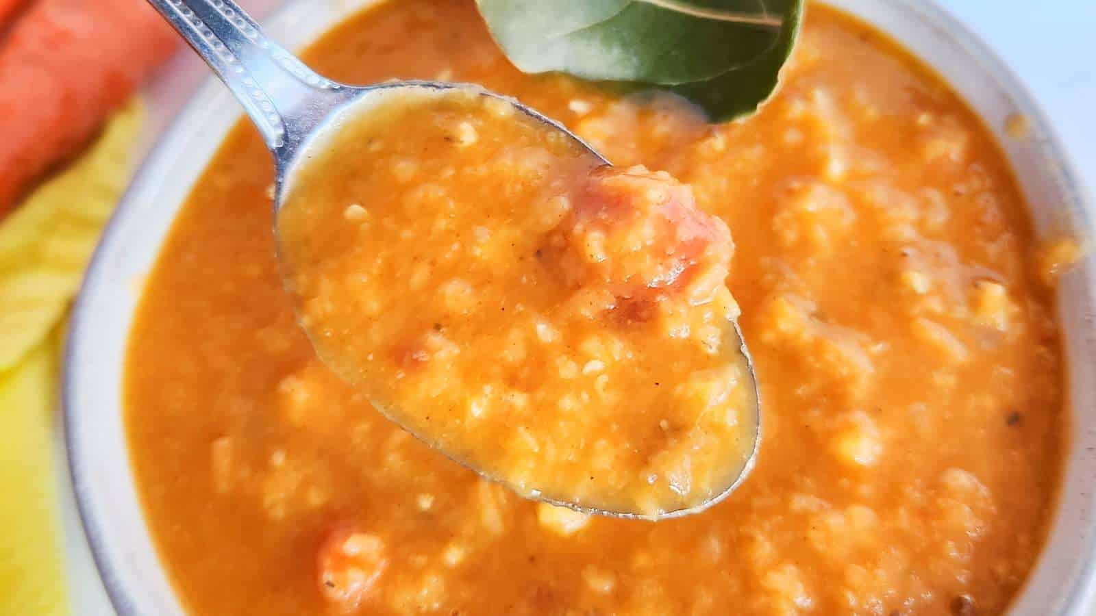 A spoonful of carrot and red lentil soup in a bowl.