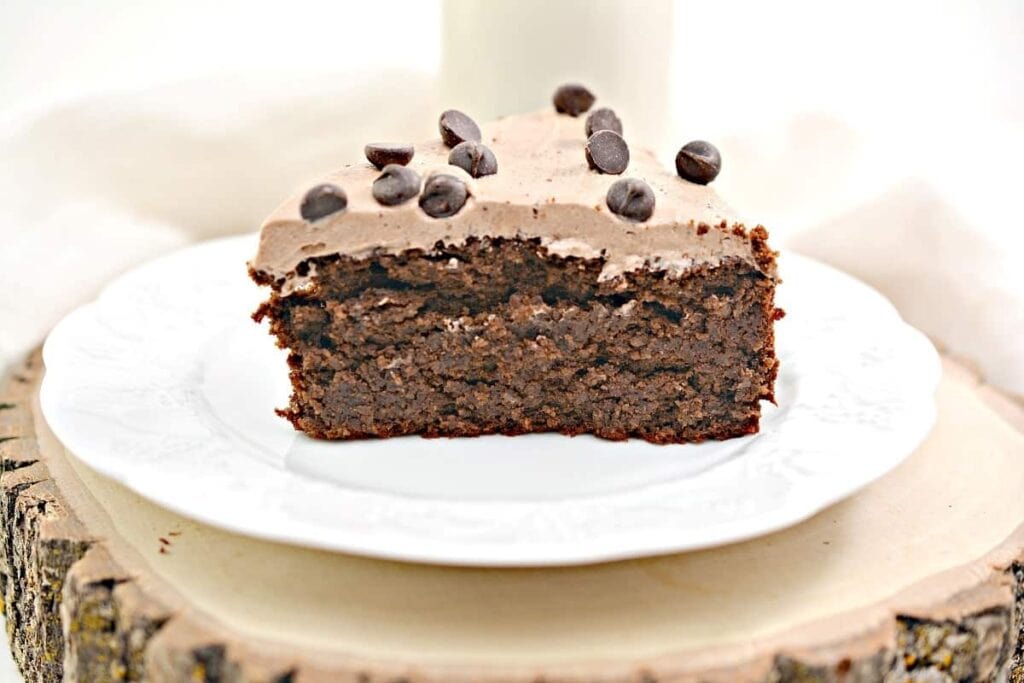 A slice of chocolate cake with chocolate icing on a plate.