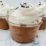 Chocolate mousse in mason jars with whipped cream and chocolate chips.