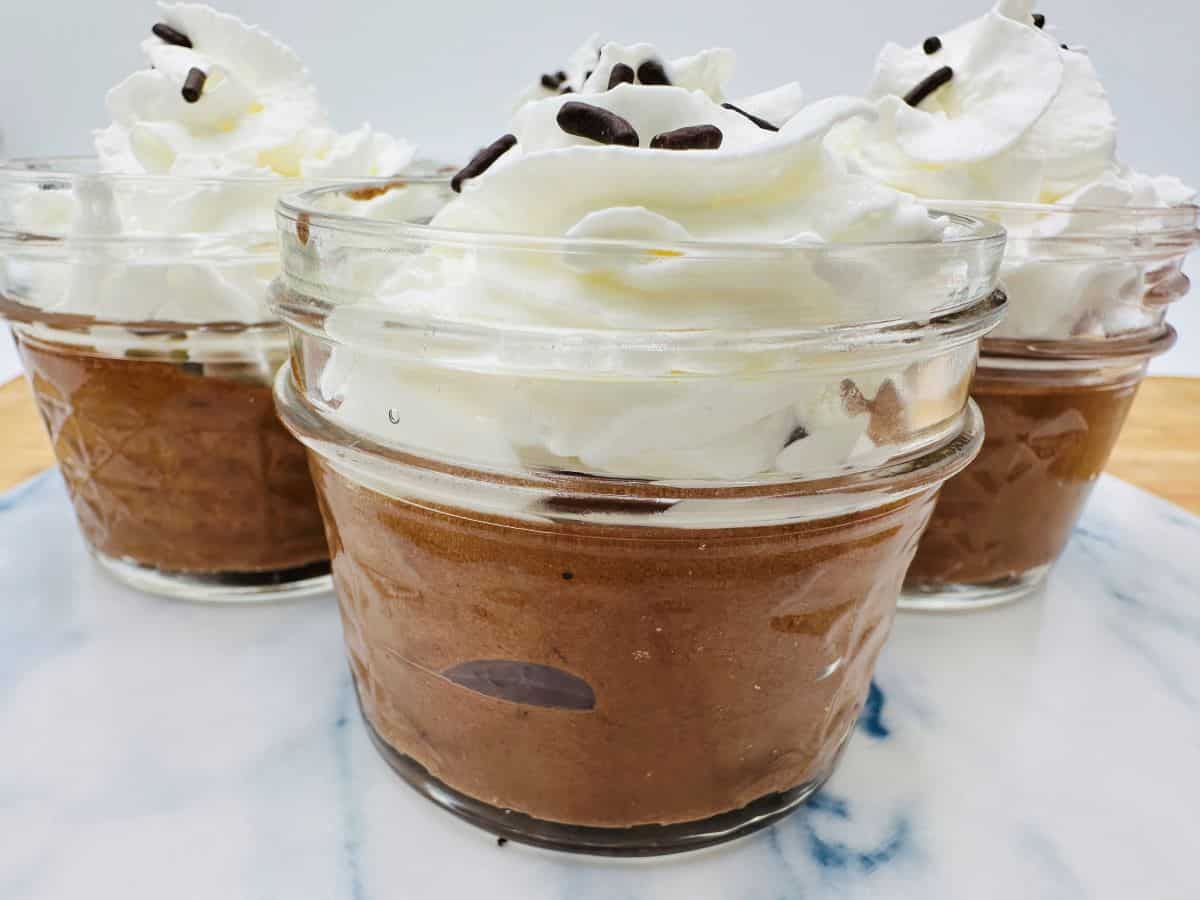 Chocolate mousse in mason jars with whipped cream and chocolate chips.