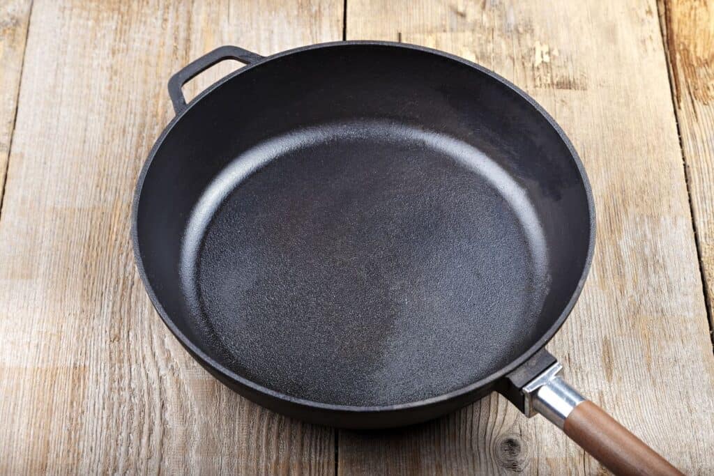 A black cast iron skillet on a wooden table.