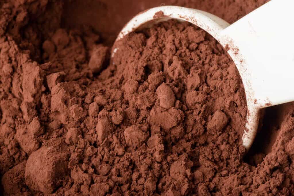 A close up of a scoop of cocoa powder.