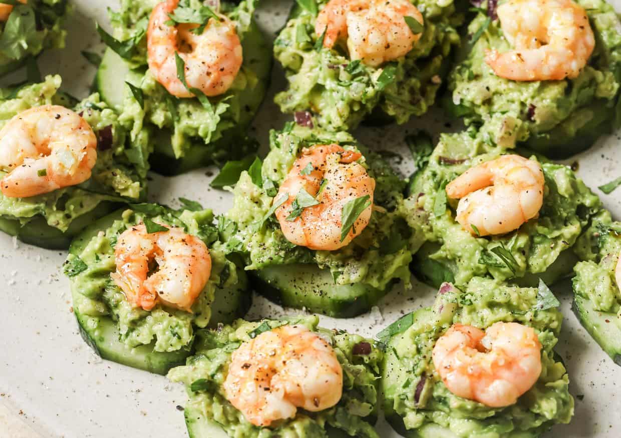 A person holding a cucumber with shrimp and guacamole.