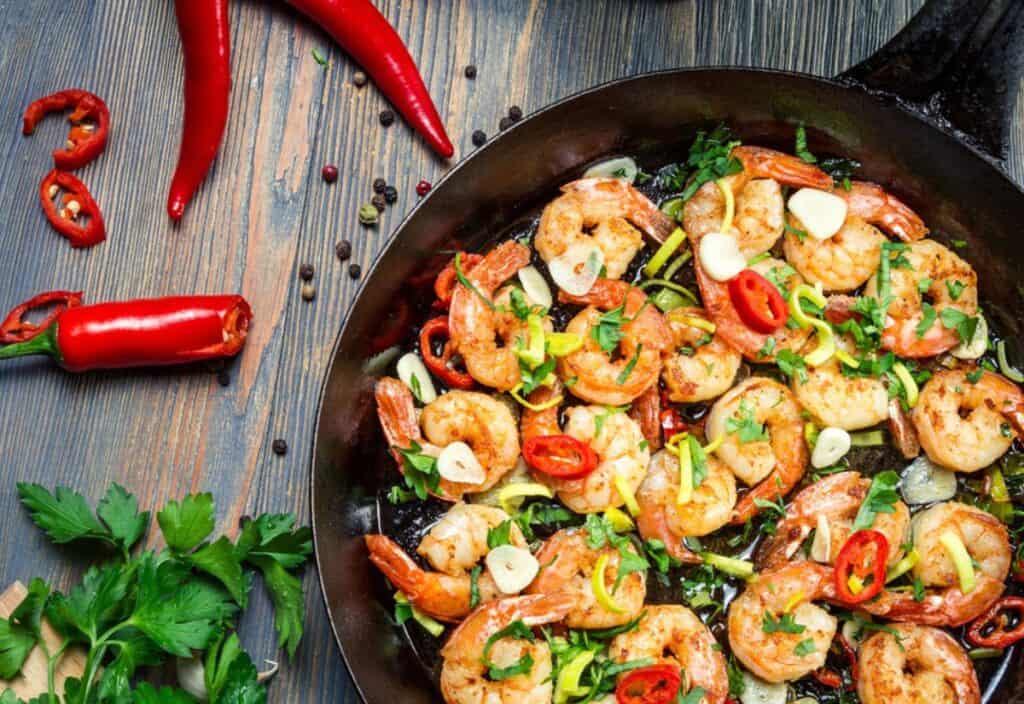 Fried shrimp in a skillet on a wooden table.