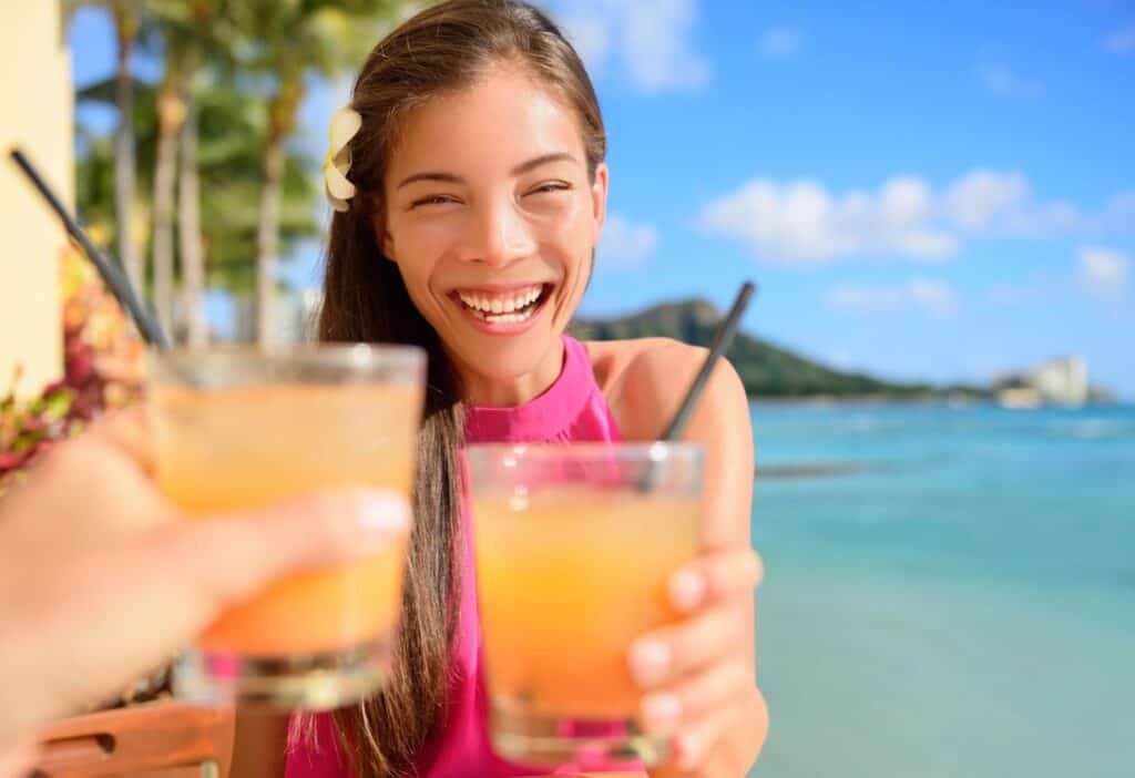 A woman is toasting with a glass on a beach.