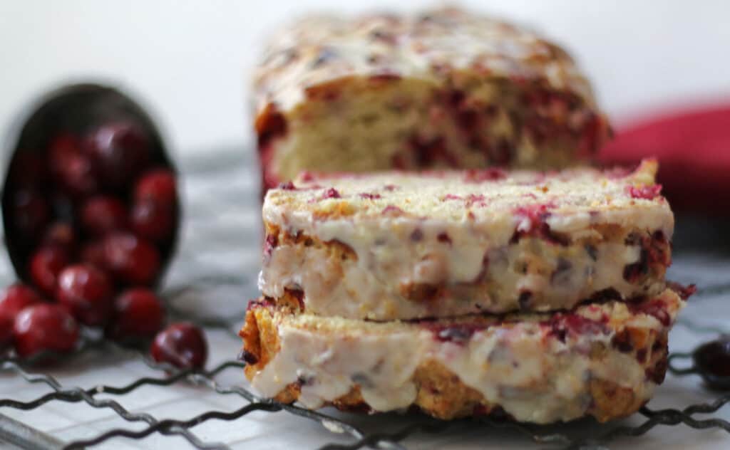 A slice of cranberry bread on a cooling rack.