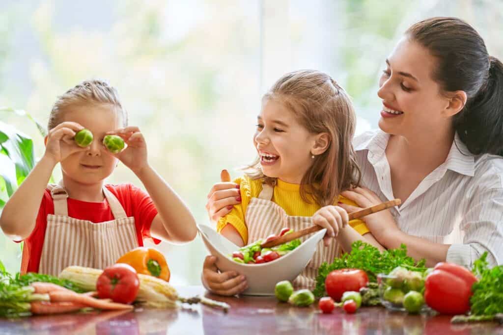 A mother and two children are eating vegetables together.