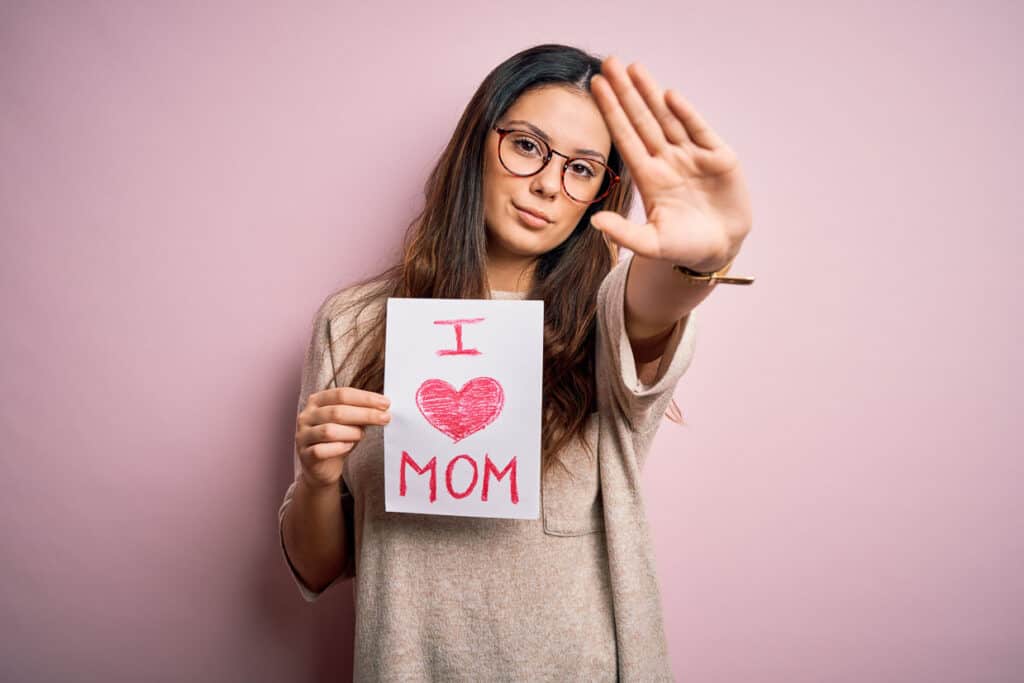A girl holding up a sign that says i love mom.