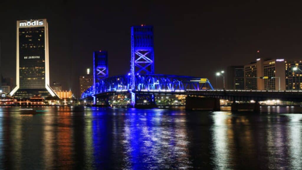 Experience Jacksonville's stunning skyline at night, featuring a striking blue bridge and towering skyscrapers. Unwind in the city that never sleeps with endless things to do.