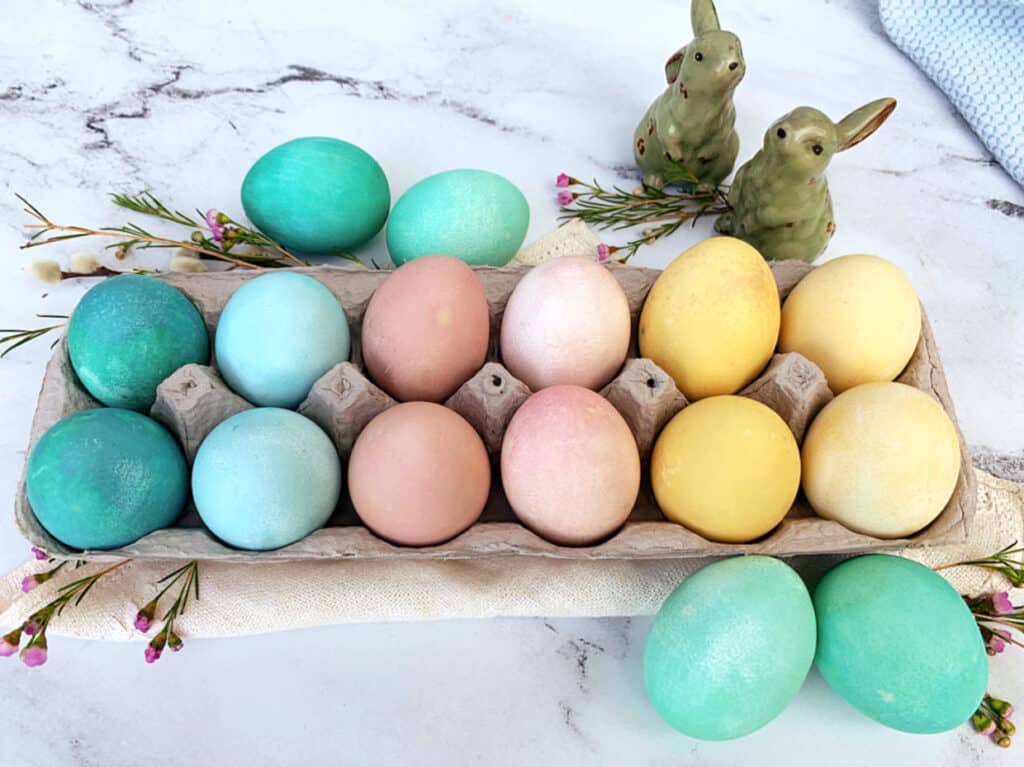 A tray of colored easter eggs on a marble table.