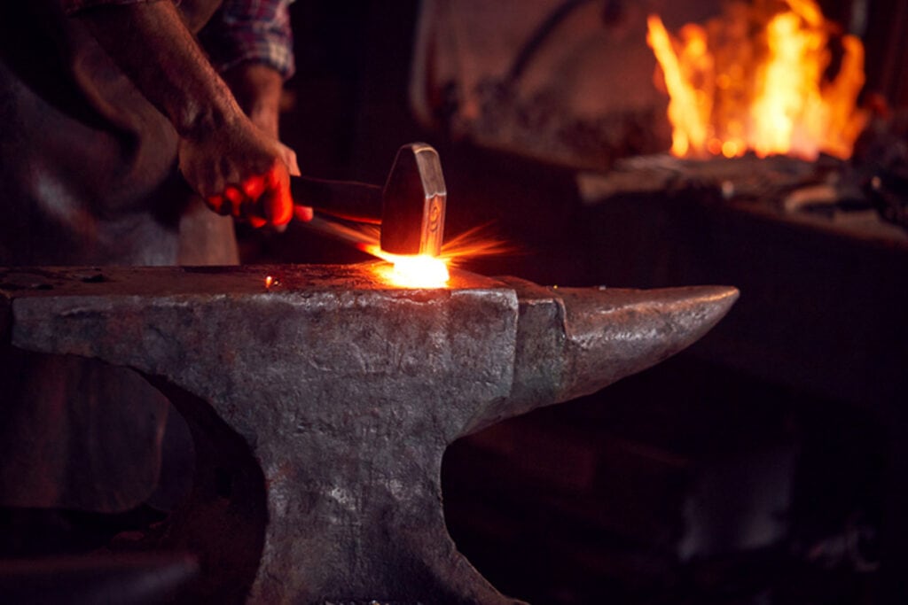 A blacksmith is working on a blacksmith's anvil.
