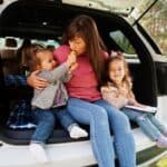 A woman and her children are sitting in the trunk of a car.