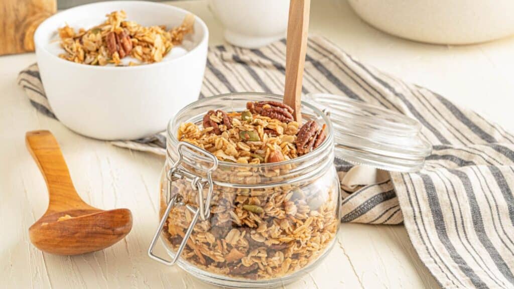 Granola in a glass jar on a wooden table.