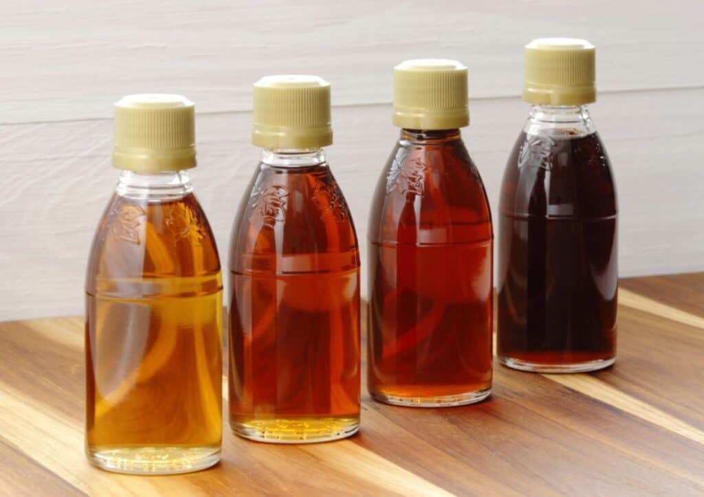 Four bottles of maple syrup showcased on a rustic wooden table.