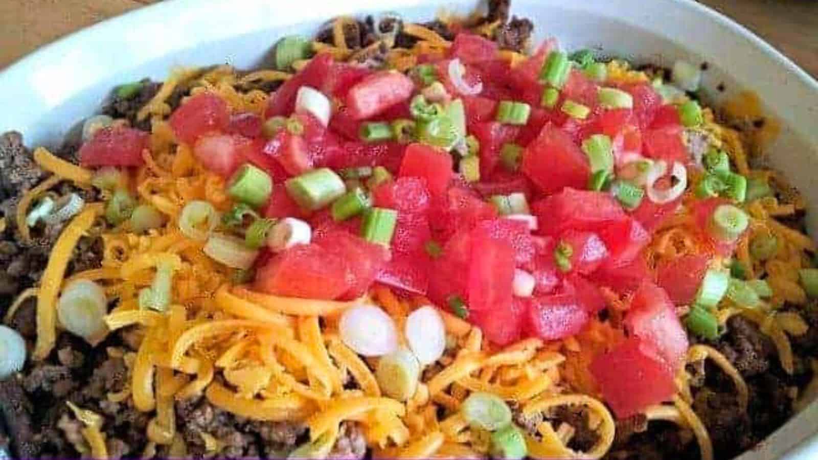Image shows a closeup of a casserole dish filled with non-traditional seven layer dip.