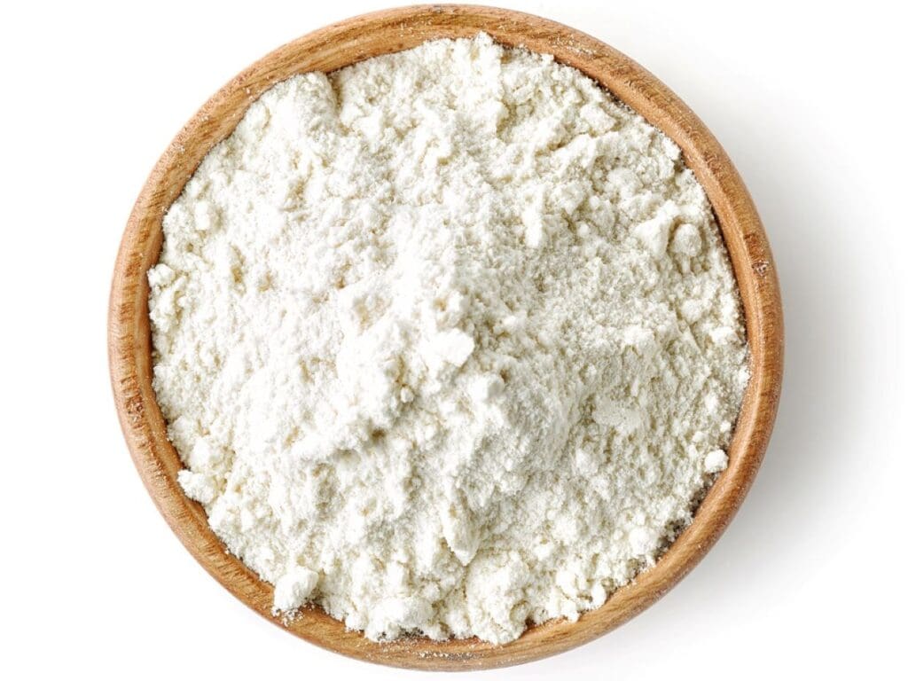 Oat flour in a wooden bowl on a white background.