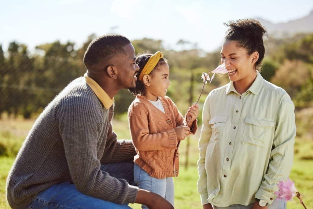 A family blowing a dandelion in a field.