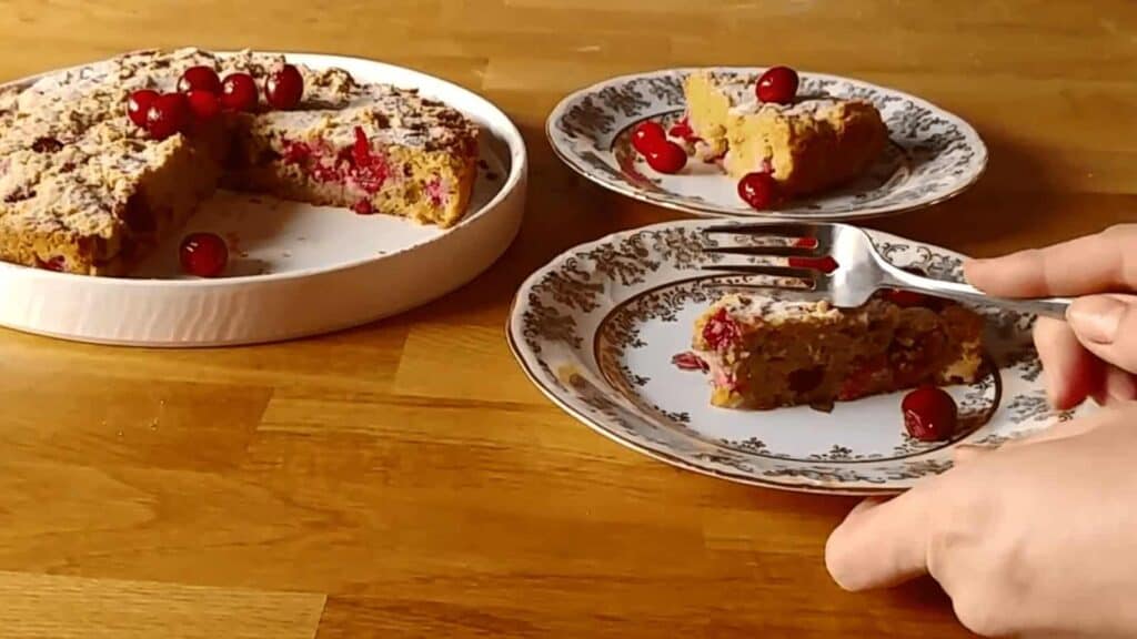 A person cutting a piece of cranberry coffee cake.