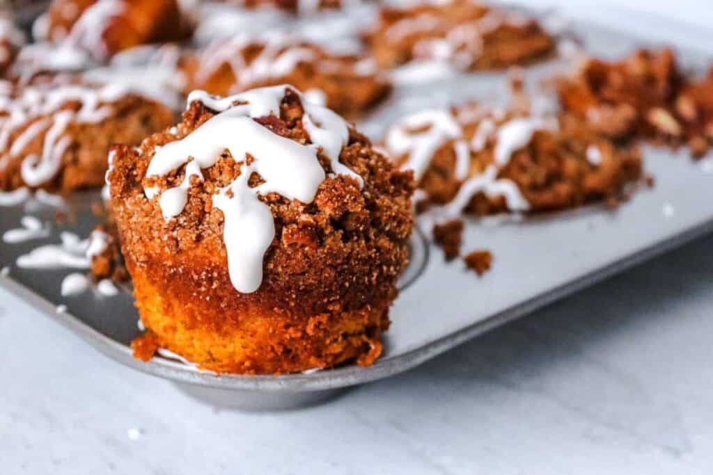 Muffins in a pan with icing on top.