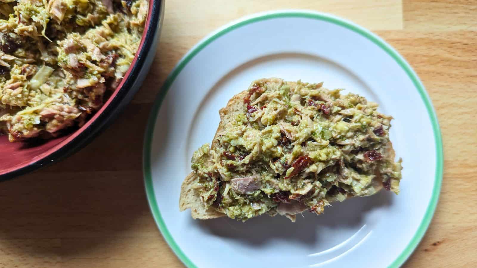 Image shows an overhead shot of an open face Pesto and Sundried Tomato Tuna Salad sandwich.