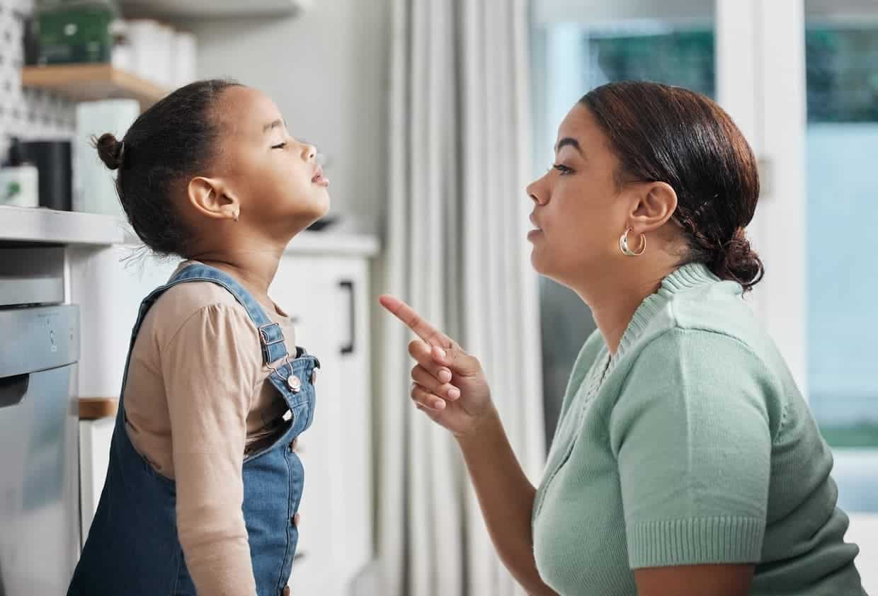 A mother and daughter having power struggle pointing at each other in the kitchen.