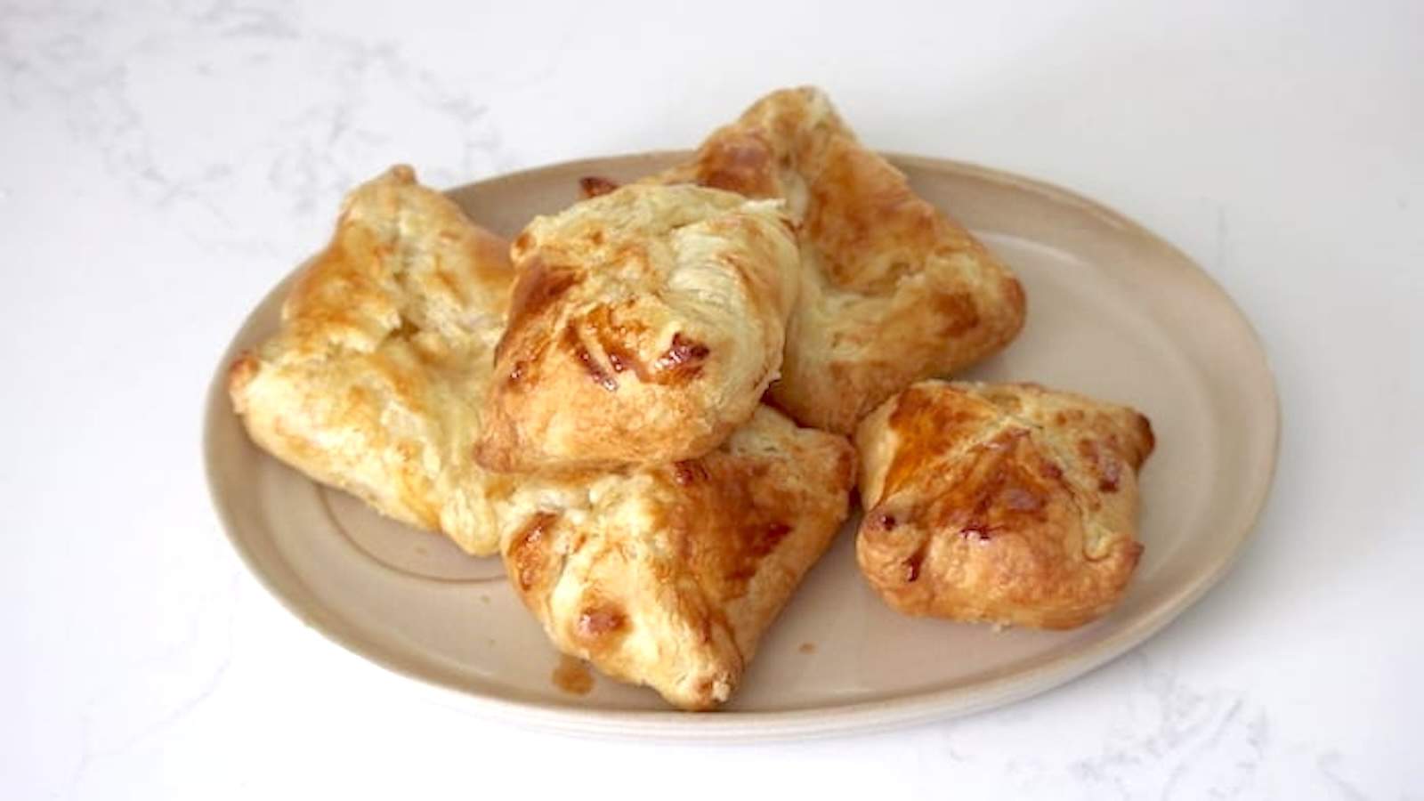 A plate with puff pastry cheese pockets on it.