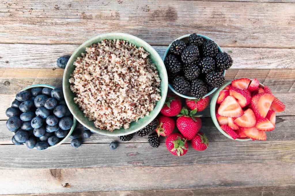 A bowl of quinoa and berries on a wooden table.