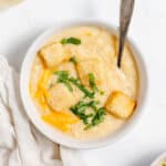 A bowl of soup with croutons and parmesan cheese.