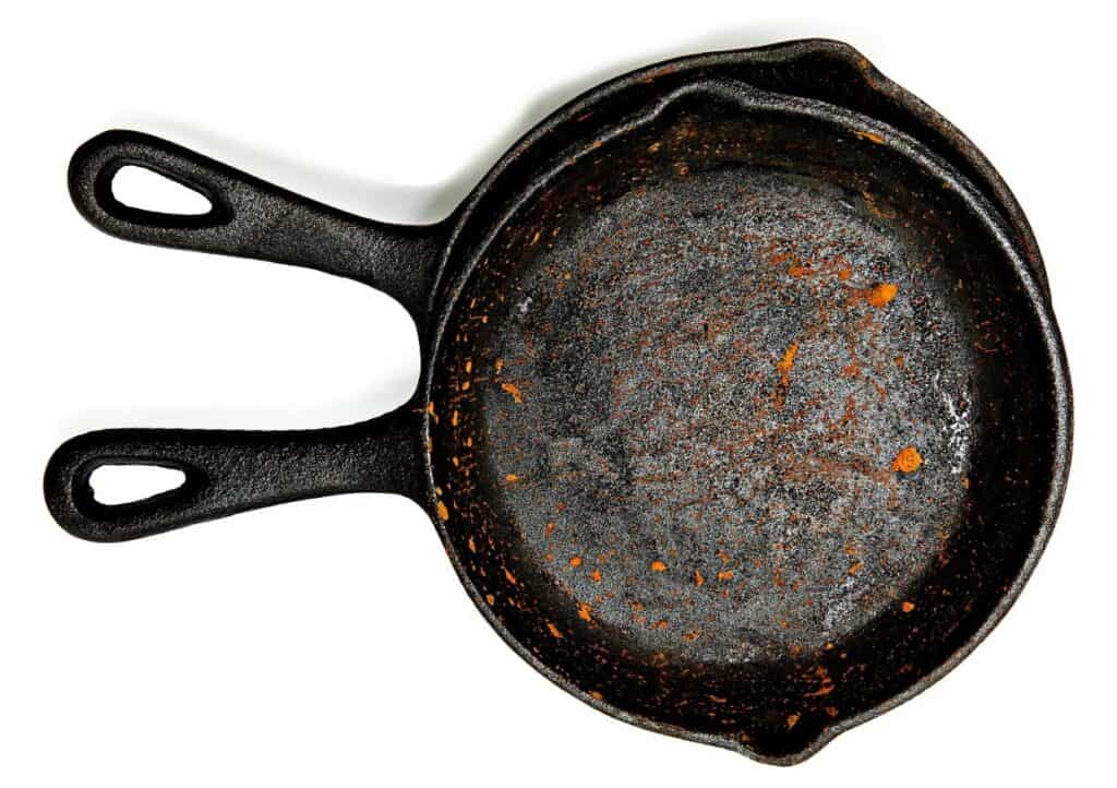 Two rusted cast iron skillets on a white background.