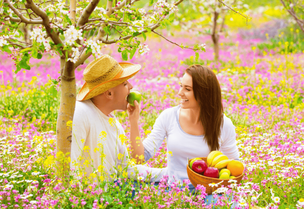A man and a woman sitting in a field of flowers.
