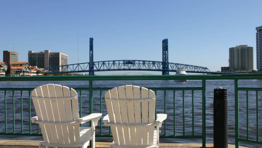 Enjoy the view of the water from two white chairs on a railing, a perfect spot to relax in Jacksonville.