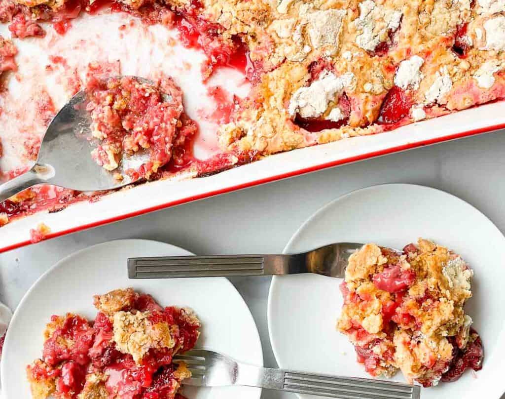 Strawberry cobbler in a white dish with a fork.